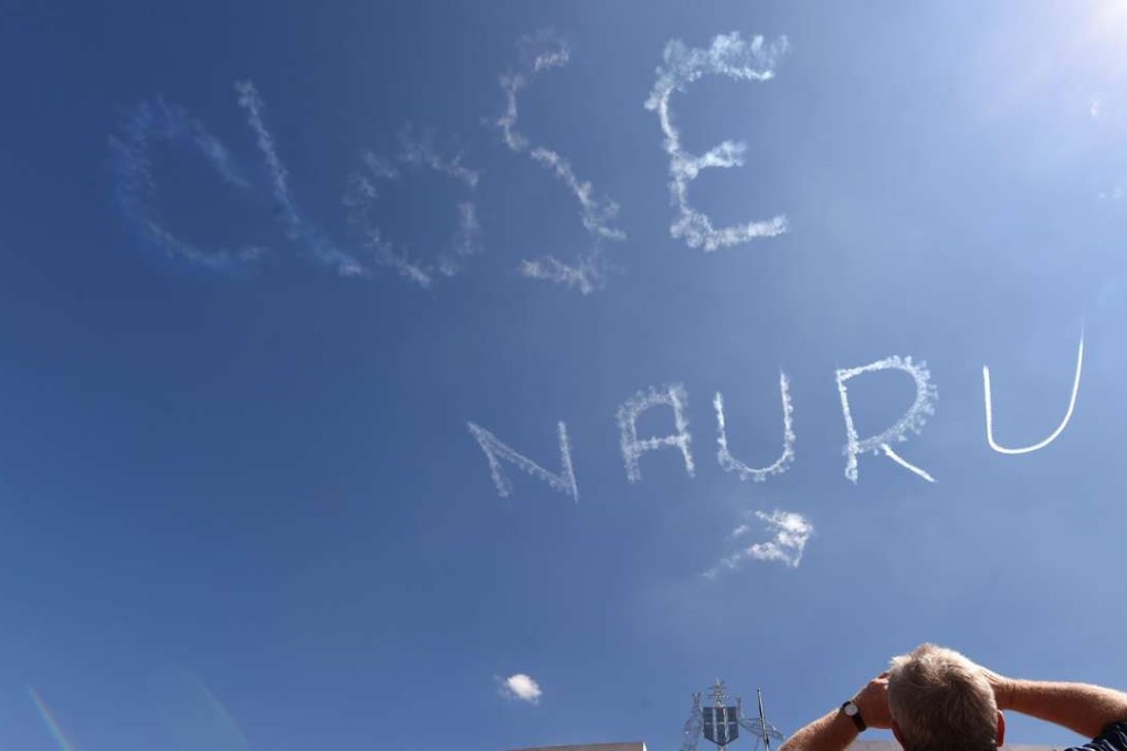 A man watches at a sky-writing reading 'CLOSE NAURU' above Parliament House in Canberra, Australia on February 17, 2015. The protest was put together by three individuals calling themselves 'Unaligned Individuals'. Manus island, in northern Papua New Guinea, is used by Australia as an immigration detention and asylum seeker processing centre, where illegal immigrants are kept for long times. Photo: EPA
