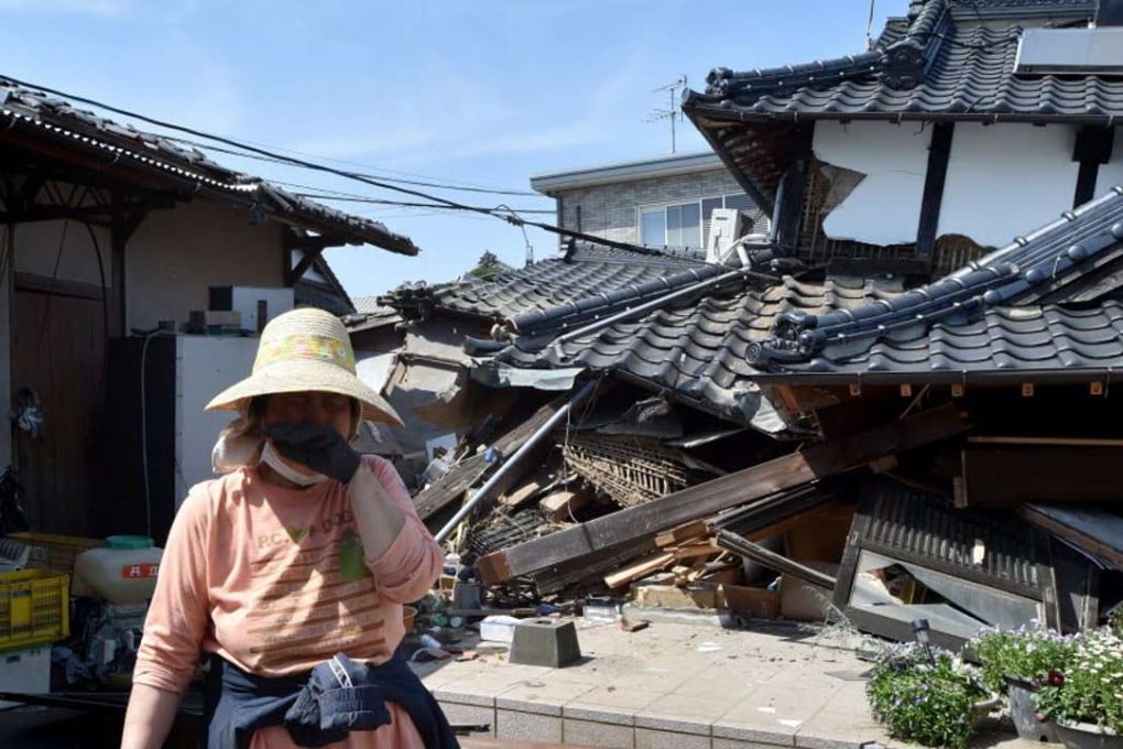 A woman stands in front of her damaged house in Mashiki, Kumamoto prefecture. Photo: AFP