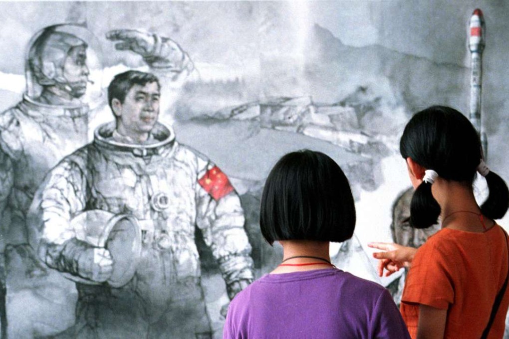 Children study a poster depicting Chinese astronauts preparing for a launch at an art exhibition. Photo: AP
