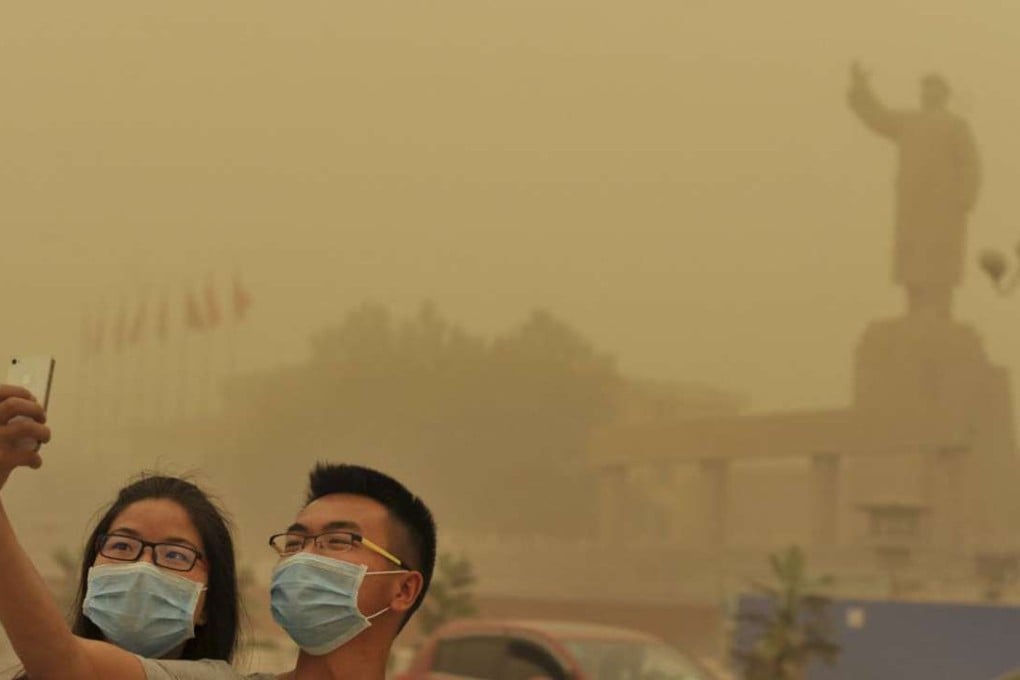 Two residents take a selfie near a statue of Chairman Mao Zedong during a sandstorm in Kashgar, Xinjiang. Photo: Reuters