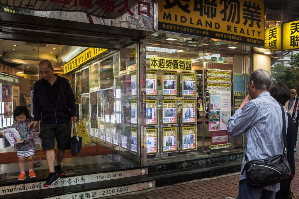 People look at residential property advertisements displayed in the window of a real estate office in the North Point district of Hong Kong. Photo: Bloomberg, Billy H.C. Kwok