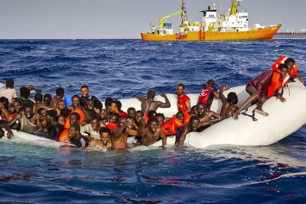 In this photo taken on Sunday, migrants call out for help from a sinking dinghy as they are approached by the SOS Mediterranee's ship Aquarius (background), off the coast of the Italian island of Lampedusa. The sinking of a different boat headed for Italy last week may have resulted in the deaths of 500 migrants. Photo: AP