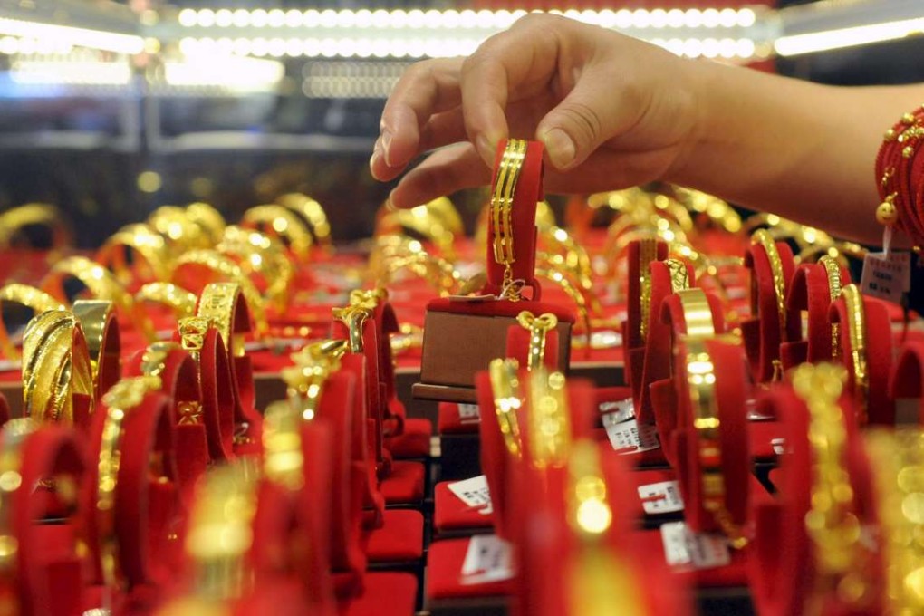 A saleswoman displays a gold bracelet as she poses for pictures at a jewellery shop in Lin'an, China on July 29, 2015, Photo: Reuters