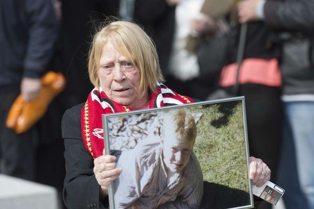 Mary Corrigan shows a photograph of her son Keith McGrath, who was 17-year-old when he died in the Hillsborough disaster, as she emerges from court after hearing the unlawful killing verdict at the Hillsborough inquest at the coroner’s court in Warrington. Photo: EPA