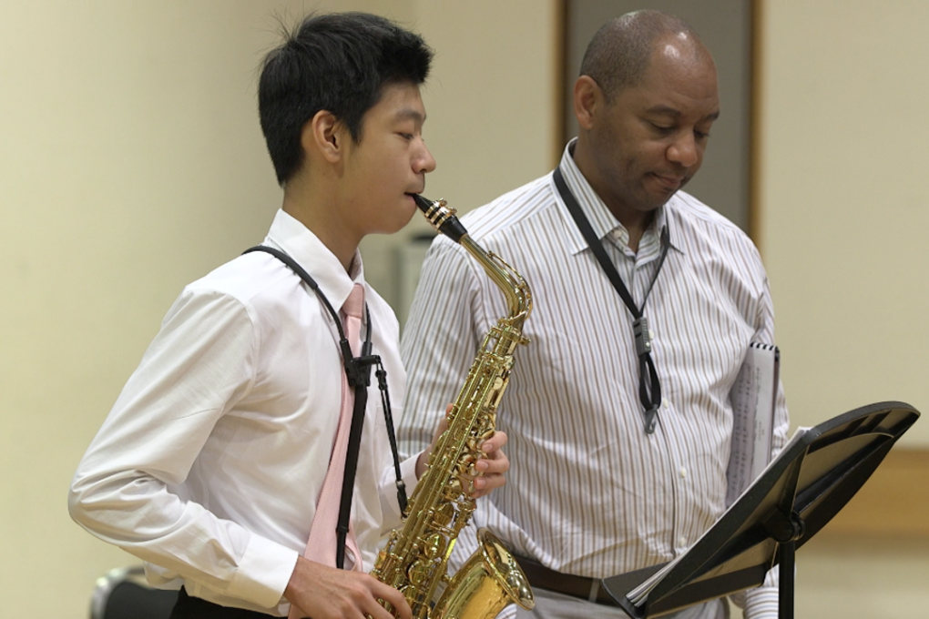 Branford Marsalis listens to Hongkonger James Cheng play the saxophone at a masterclass.