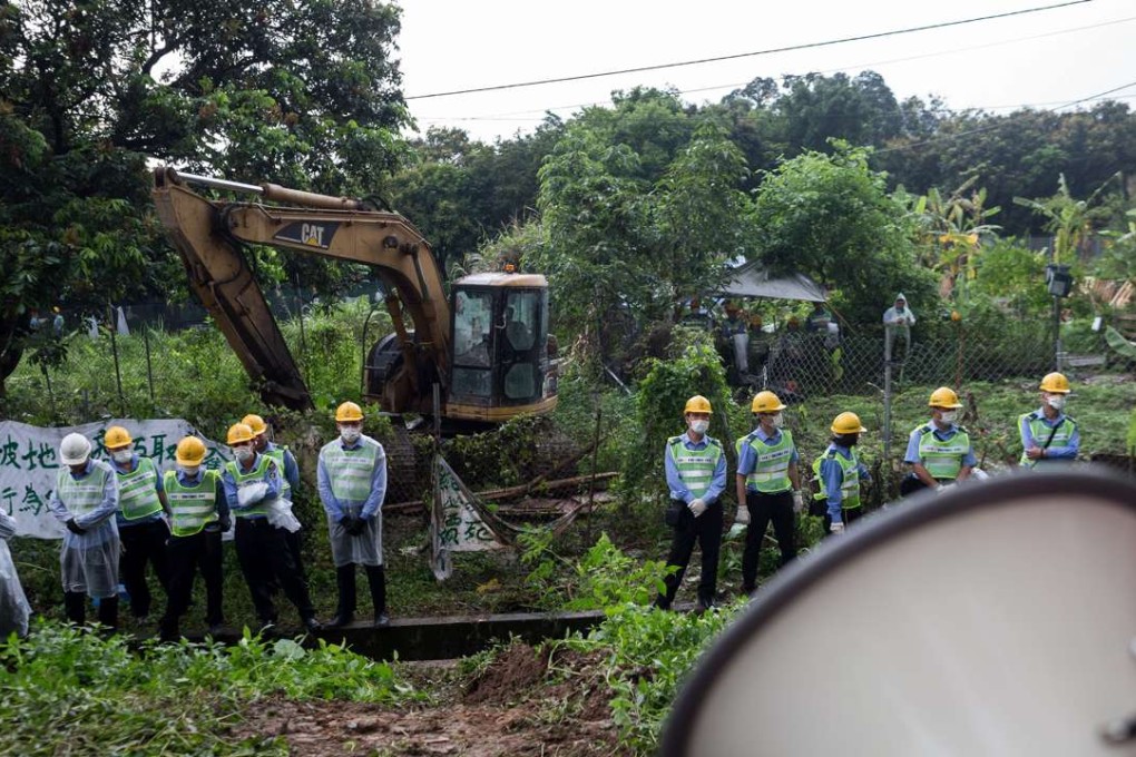 Security personnel stand guard next to an excavator in Ma Shi Po village, Fanling. Photo: JEROME FAVRE