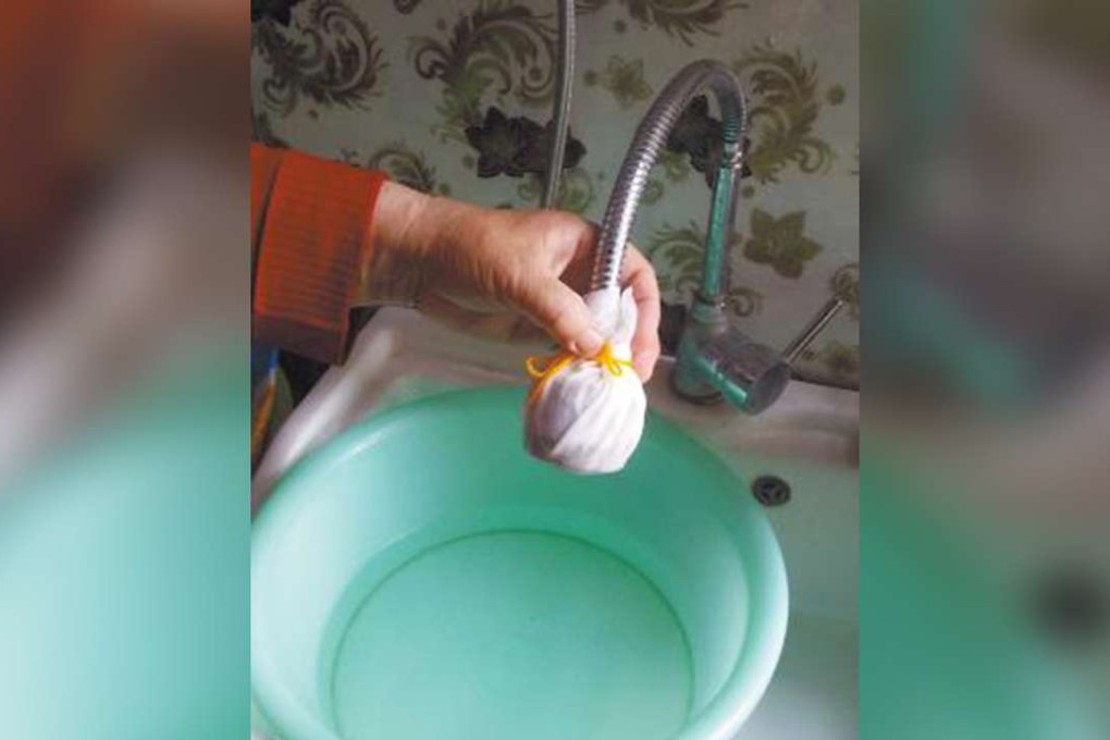 A resident in Shijiazhuang puts a makeshift sieve over a tap to stop worms getting through. Photo: Yanzhao Evening News