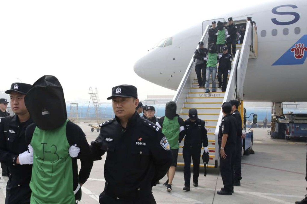 Mainland and Taiwanese suspects involved in wire fraud are escorted off a plane upon arriving at the Beijing Capital International Airport in Beijing. Photo: Xinhua