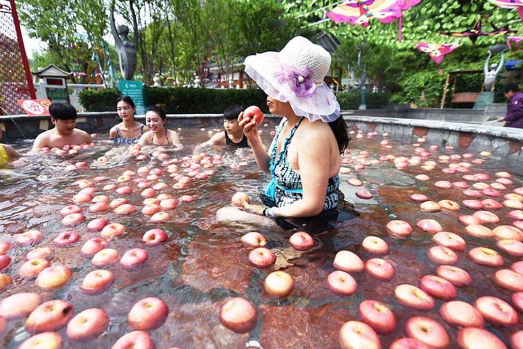 Bobbing for apples. A woman bather eats an apple in the hotspring. Photo: Youth.cn.