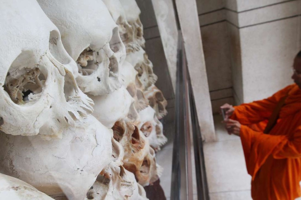 A Cambodian Buddhist monk photographs the remains of victims who died during the Khmer Rouge regime. Photo: EPA