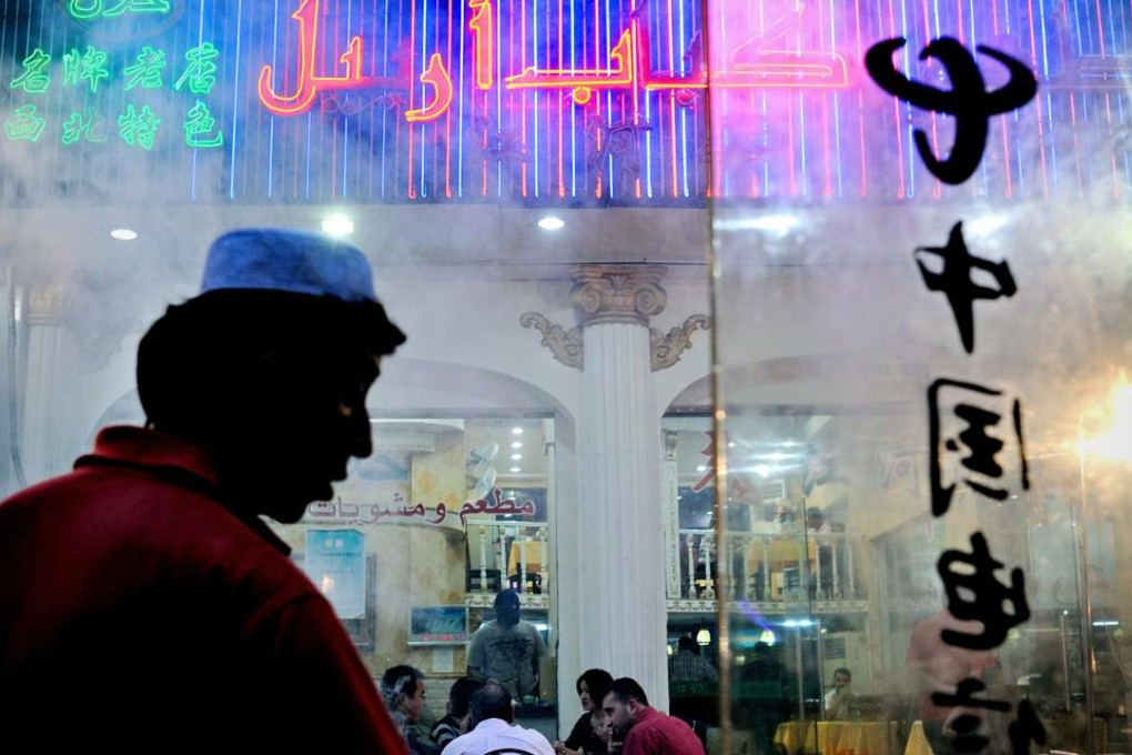 A restaurant worker grills lamb while people eat at a Muslim restaurant in Yiwu, Zhejiang province. Photo: AFP