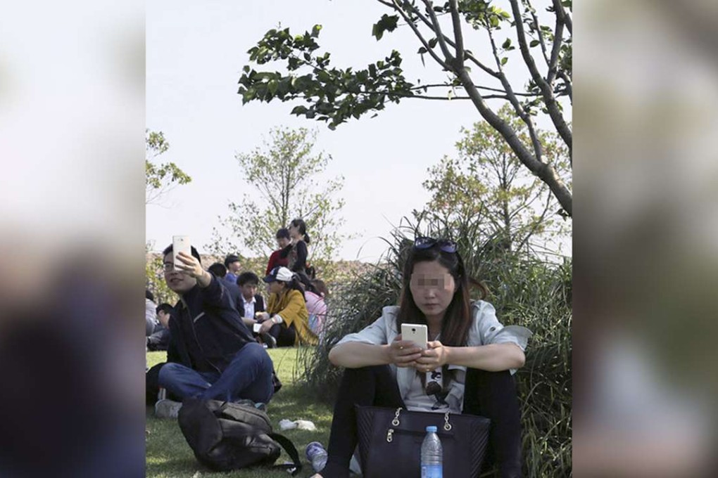 A woman, with her shoes off, sits on the lawn in Disney Town, Shanghai, on Monday. Photo: SCMP Pictures