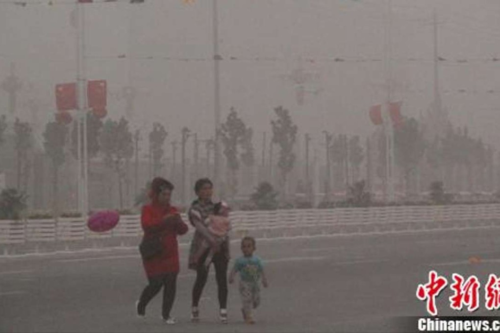 A family runs for cover during the sandstorm in Xinjiang. Photo: Chinanews.com