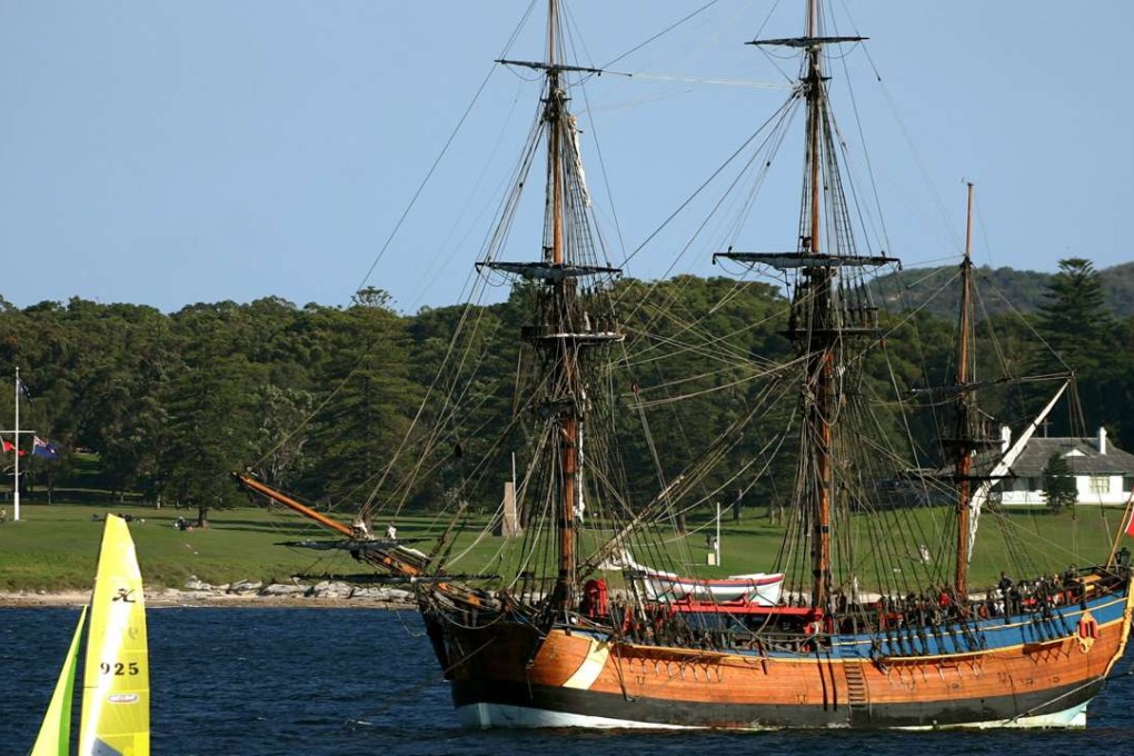 A small sailing boat sails past the replica of the famous 18th century ship The Endeavour as it sits anchored in Botany Bay, Australia in 2005. Photo: Reuters