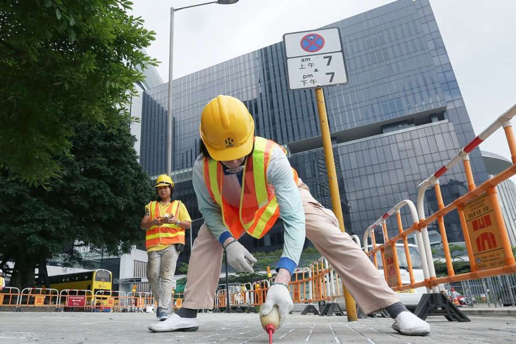 Workers applying glue to the gaps between bricks on the pavement outside Legco. Photo: SCMP Pictures