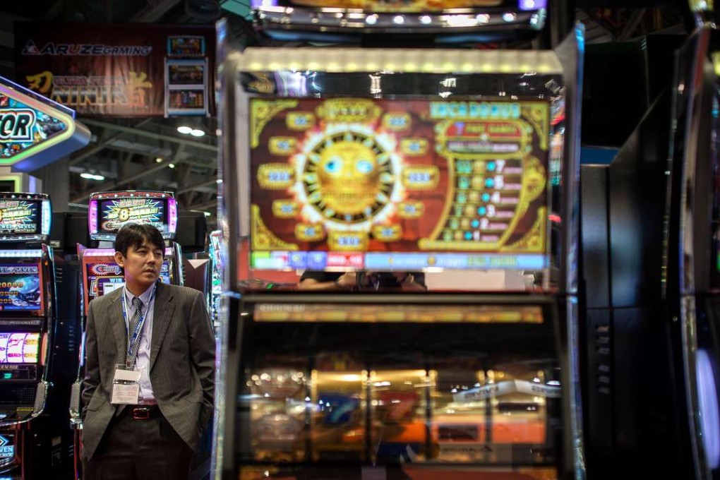 A 2014 file photo shows a visitor strolling by gambling machines at a booth of the Global Gaming Expo Asia in the worlds biggest gambling hub of Macau. Photo: AFP