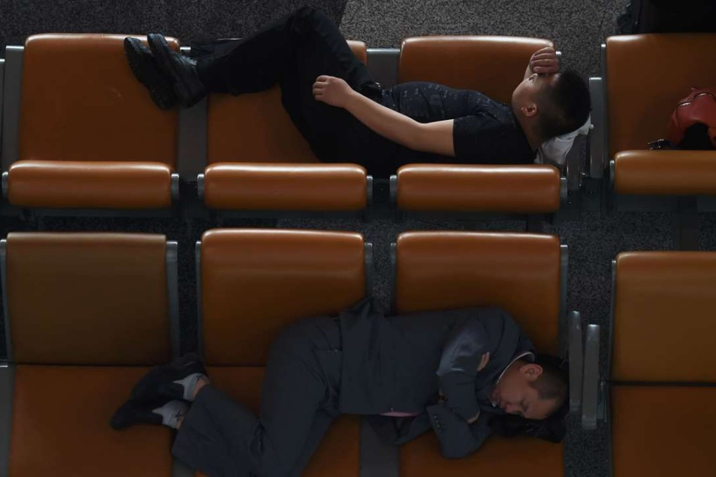 Two men sleep on seats at Beijing International Airport. Photo: AFP