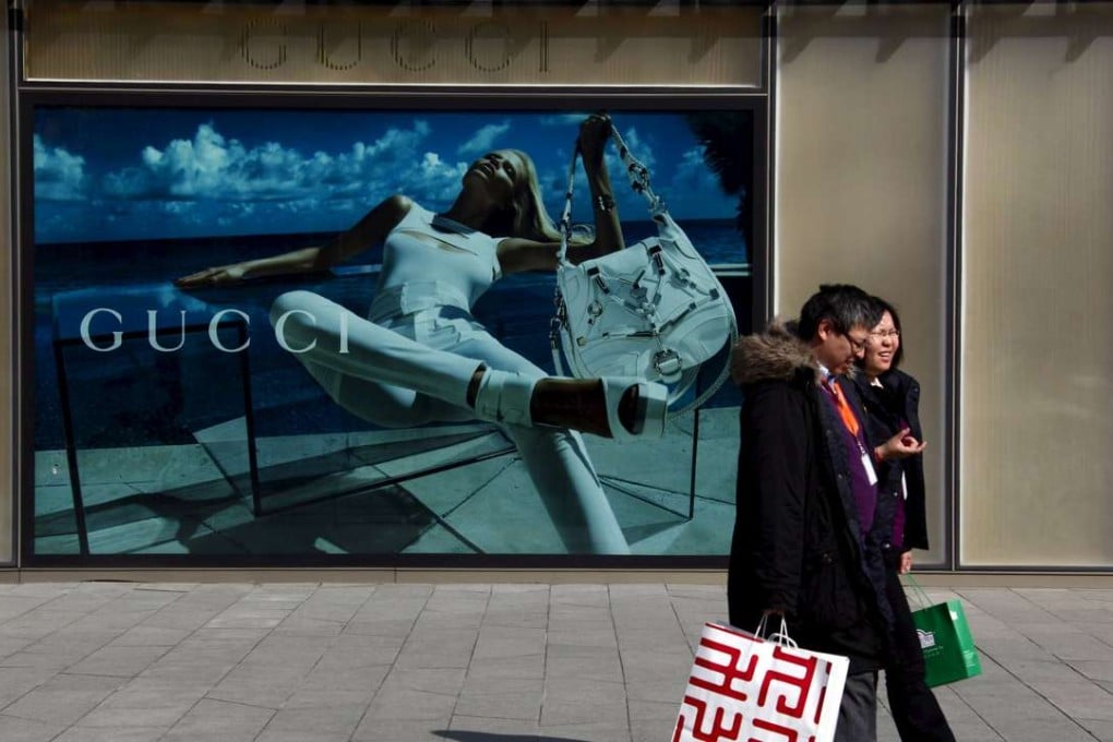 Shoppers walk past a billboard for fashion label Gucci in Beijing. The Italian luxury goods powerhouse is considering adding China to the 28 countries and regions where it already sells through its website. Photo: Reuters