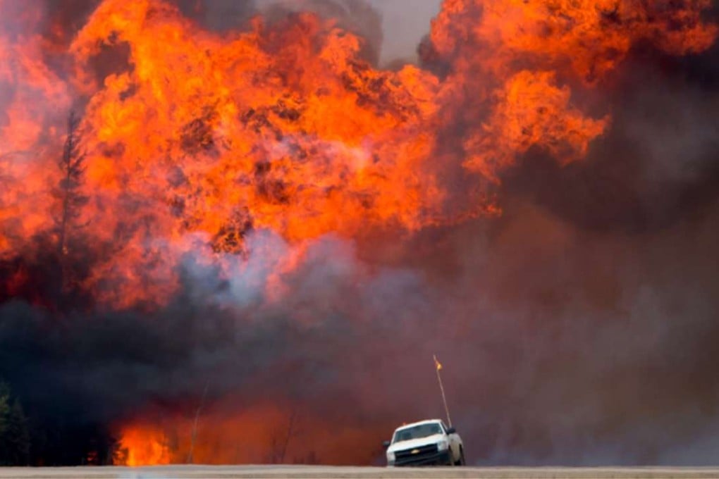 A wildfire burns behind an abandoned truck on Alberta Highway 63 near Fort McMurray. Photo: Bloomberg