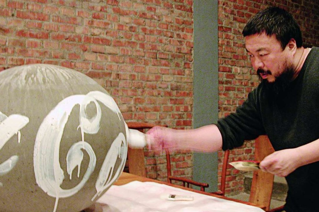 Ai Weiwei at work, adding a Coca-Cola logo to a stone ball.