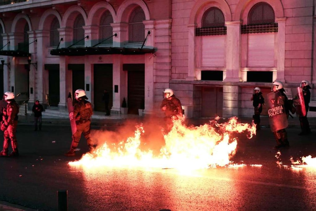 Greek police stand guard amid molotov cocktails thrown by protesters at a demonstration against reforms in Athens. Photo: AFP