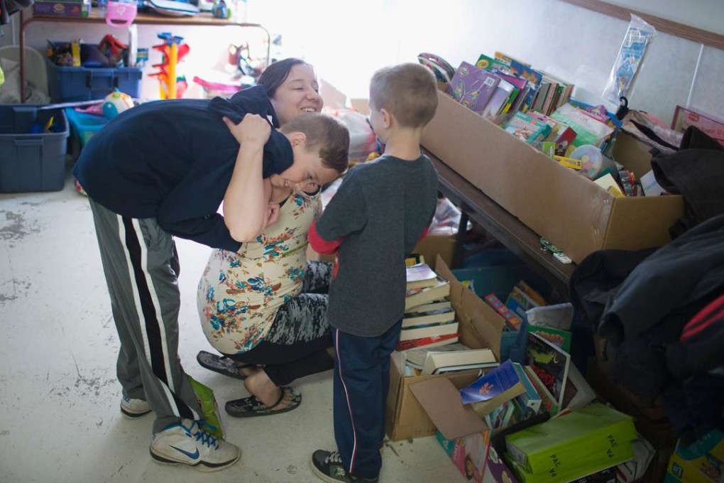 Fort McMurray evacuee Tara Payne hugs her sons Caleb (left) and Koltyn after they gave her a rose for Mother’s Day while the family was searching for necessities at a donation centre in Winding River, Alberta, on Sunday. Photo: AFP