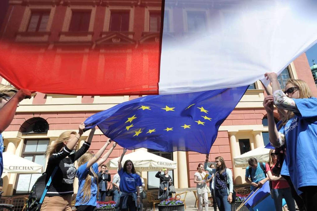 Young people in Warsaw wave the Polish and European Union flags during the yearly Schumann Parade supporting EU ideas. Photo: AP