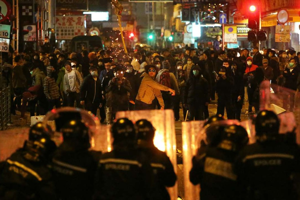 A protester throws burning paper towards police officers. Photo: Edward Wong