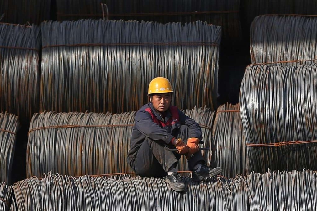 A worker rests on steel products at a steel wholesale market in Shenyang, Liaoning province. China is attempting to reduce its reliance on heavy industry, debt and government stimulus to create economic growth. Photo: EPA