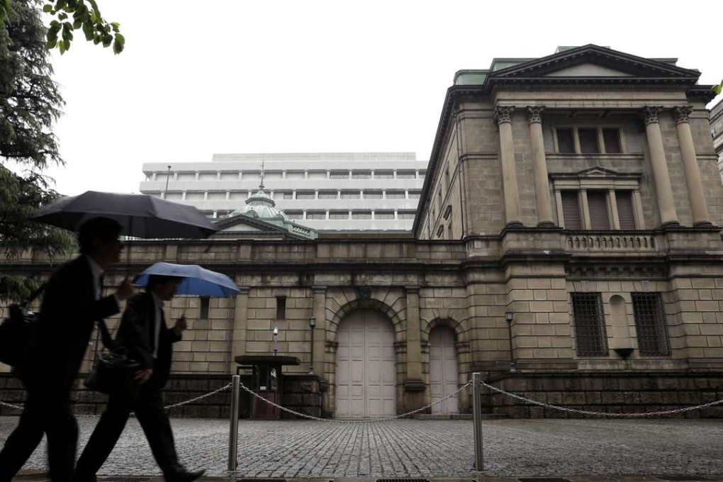 Pedestrians holding umbrellas walk past the Bank of Japan (BOJ) headquarters in Tokyo, Japan, on Thursday, April 28, 2016. The BOJ held off on expanding monetary stimulus at its monthly meeting in April, as Governor Haruhiko Kuroda and his colleagues opted to take more time to assess the impact of negative interest rates. Photographer: Bloomberg