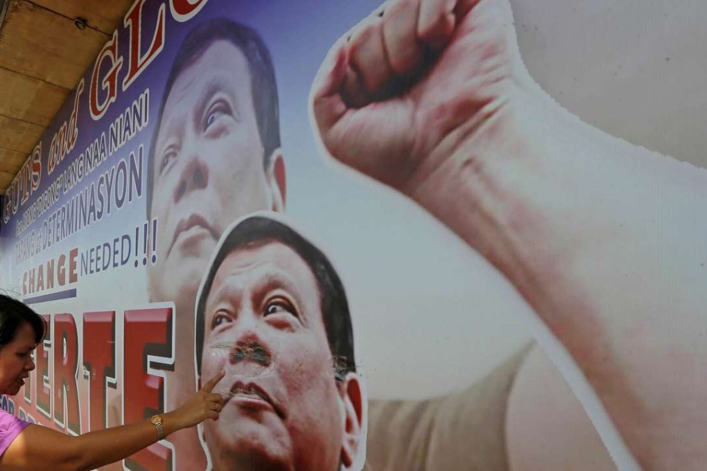 A resident in Davao City checks the damage on a tarpaulin billboard featuring Rodrigo Duterte. Photo: AP