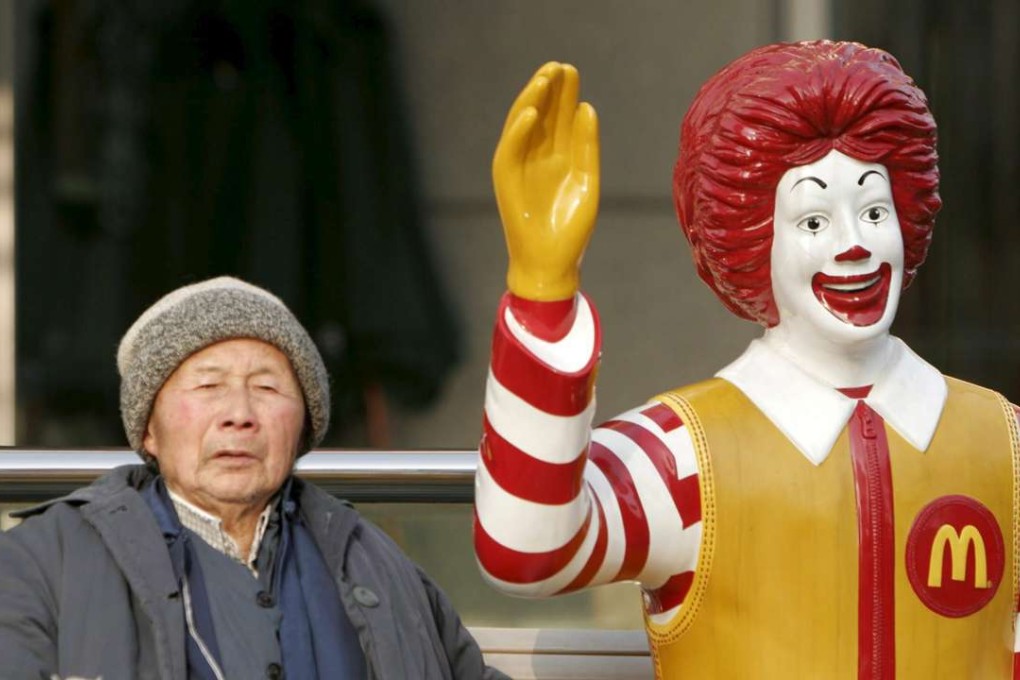 A file photo dated February 2006 showing an elderly man taking a break sitting beside a statue of Ronald McDonald in Shanghai. Photo: EPA
