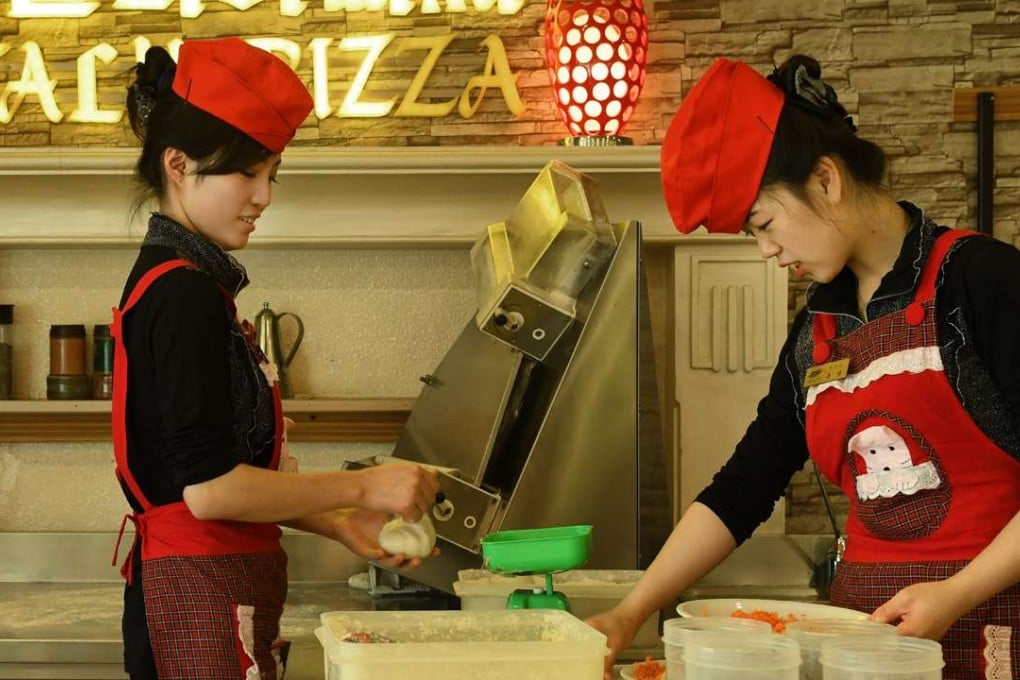Smartly uniformed women team up to make a pie at an upscale pizza restaurant on Mirae Scientists Street. Photo: Washington Post