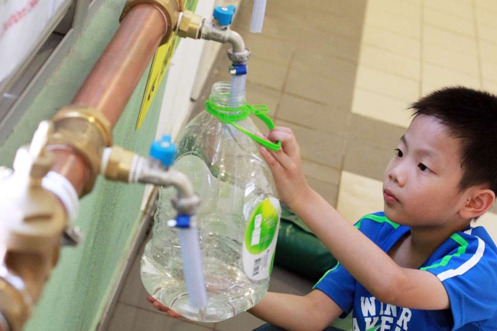 Edmond Ng Yat-long, 8, fetches water from temporary pipes on a floor at Sheung Ching House in Kai Ching Estate during the water scare last year. Photo: May Tse