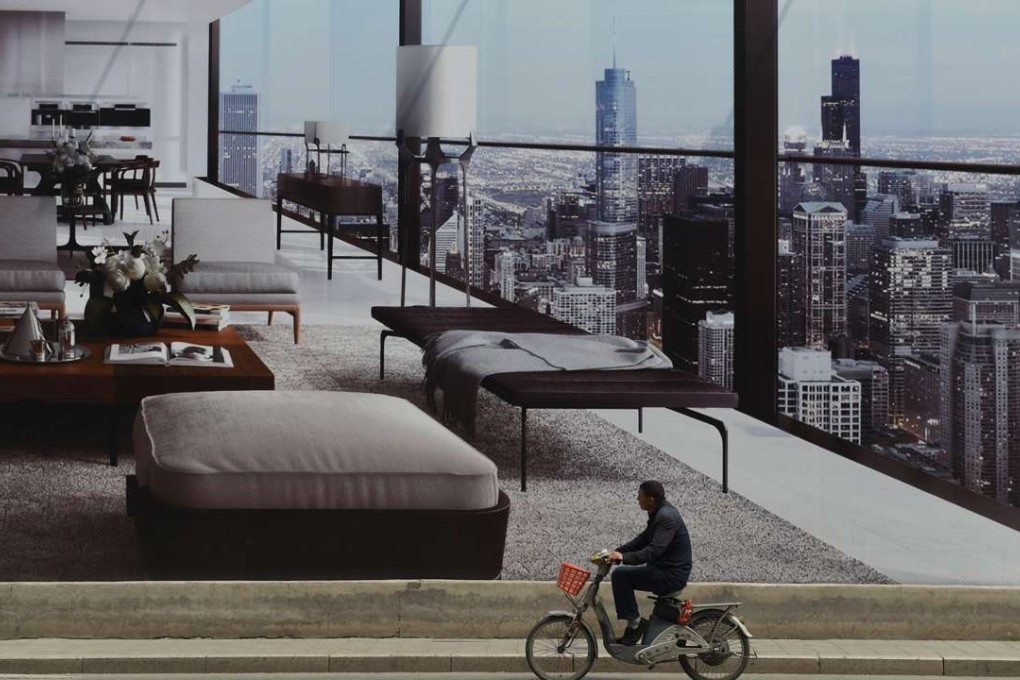 A man cycles past a billboard advertising a new housing complex outside a construction site in Beijing. Photo: AFP