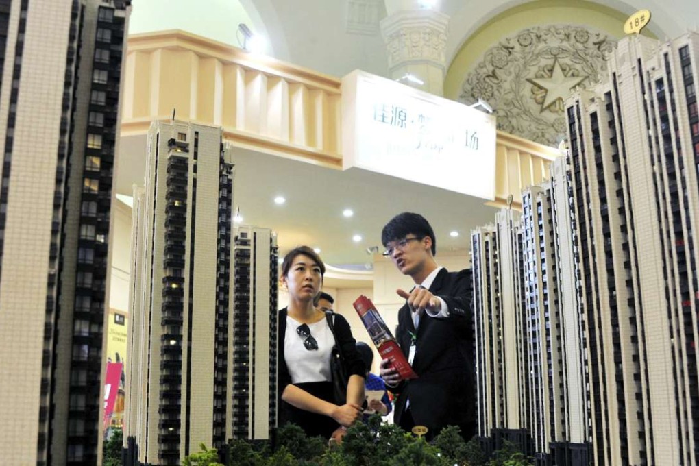 A sales assistant speaks to a customer in front of a model of a residential complex at a real estate exhibition in Shanghai. Photo: Reuters