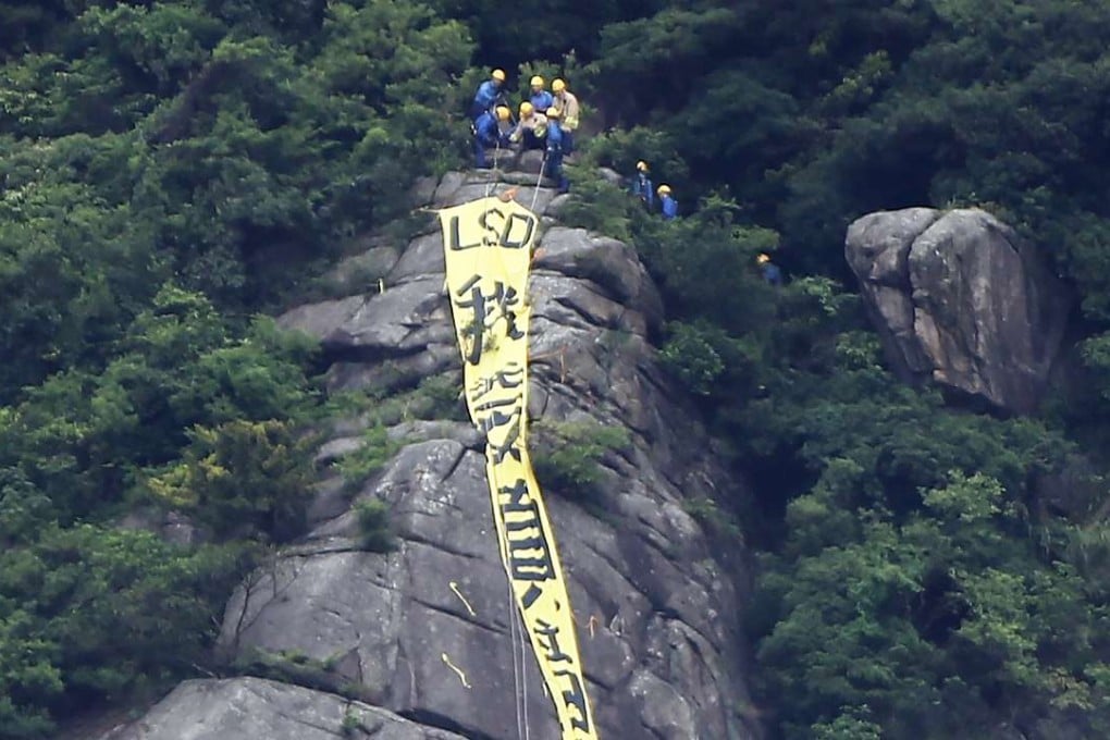 Firemen approaching the yellow banner with the words reading: ‘I want genuine universal suffrage’. Photo: Sam Tsang