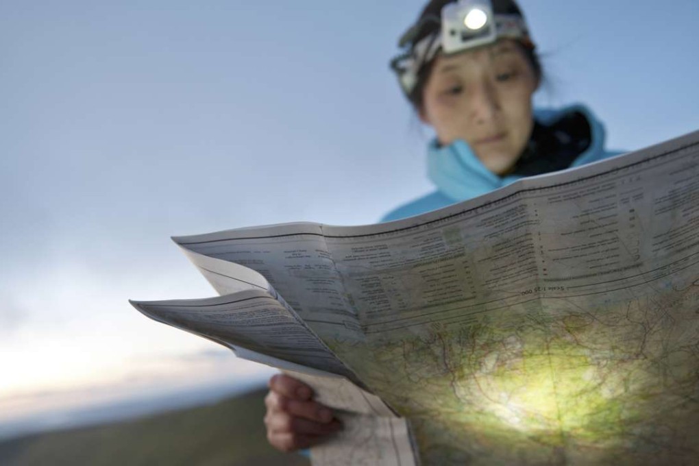 A hiker reads a map with a flashlight. Photo: Alamy.