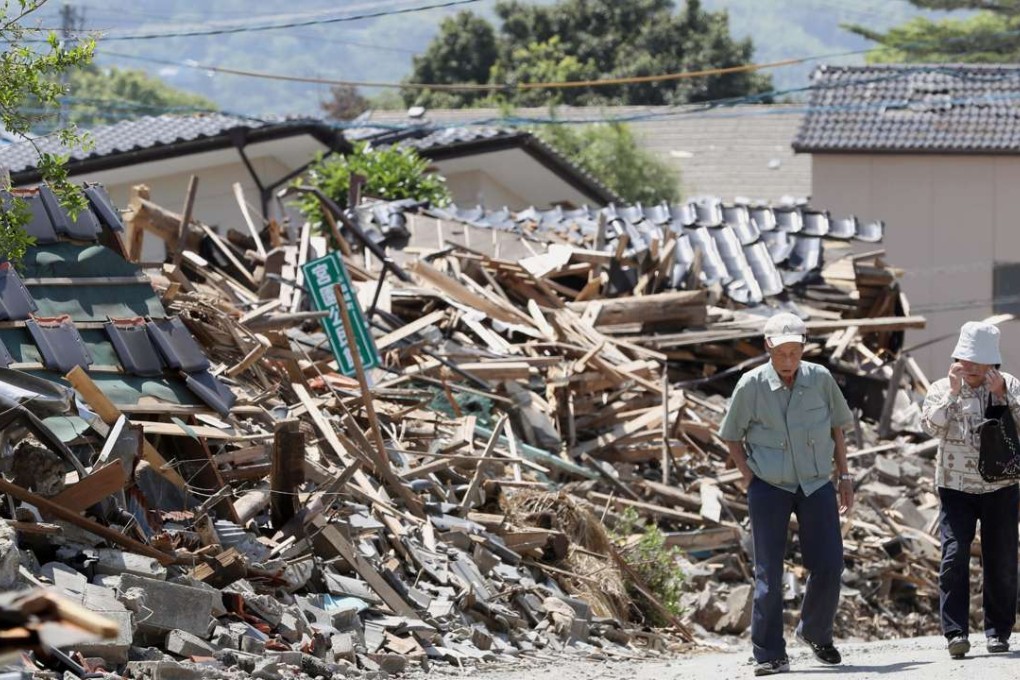 Senior citizens walk by the wreckage of earthquake-hit houses in the southwestern Japanese town of Mashiki on May 14, 2016, a month after the first of powerful earthquakes struck Kumamoto Prefecture. Photo: Kyodo