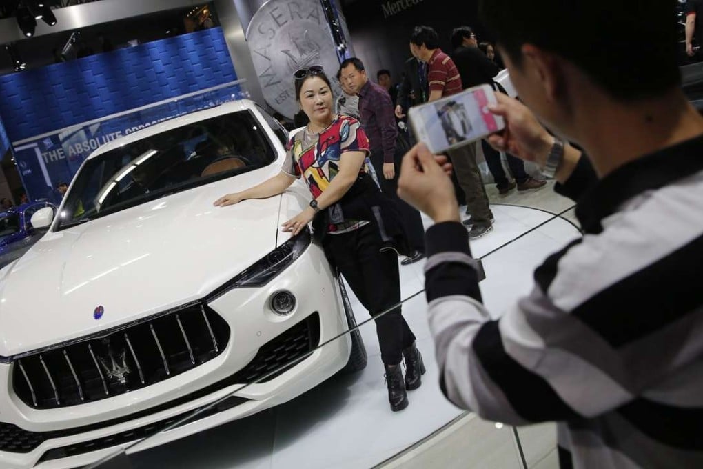 Visitors at the Auto China 2016 motor show in Beijing pose with a Maserati SUV Levante. Photo: EPA