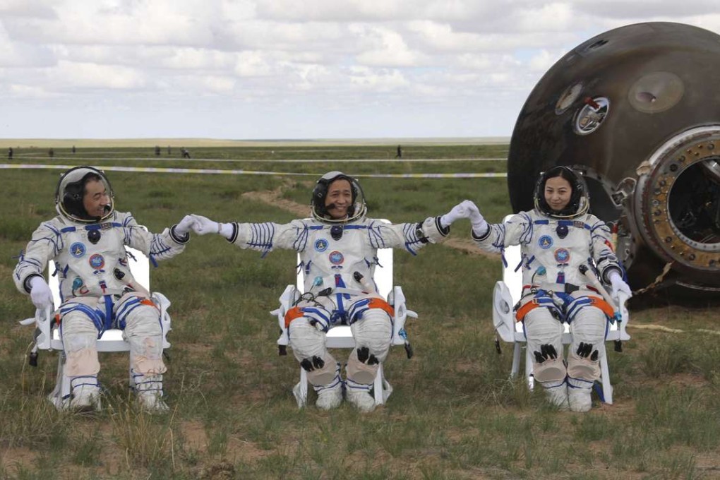 Astronauts Zhang Xiaoguang, Nie Haisheng and Wang Yaping, from left to right, join hands after leaving the re-entry capsule of China's Shenzhou 10 spacecraft in Inner Mongolia in June 2013. Photo: Xinhua