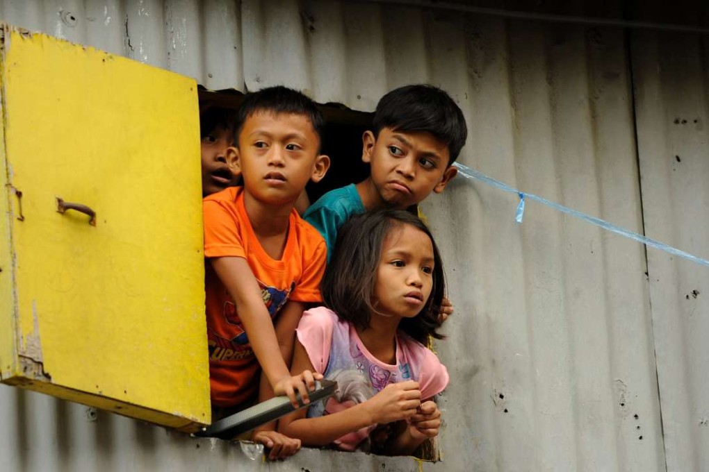 Children look out of a window in a shanty town in Manila. A third of all Asians live in extreme poverty, according to the Asian Development Bank. Photo: AFP