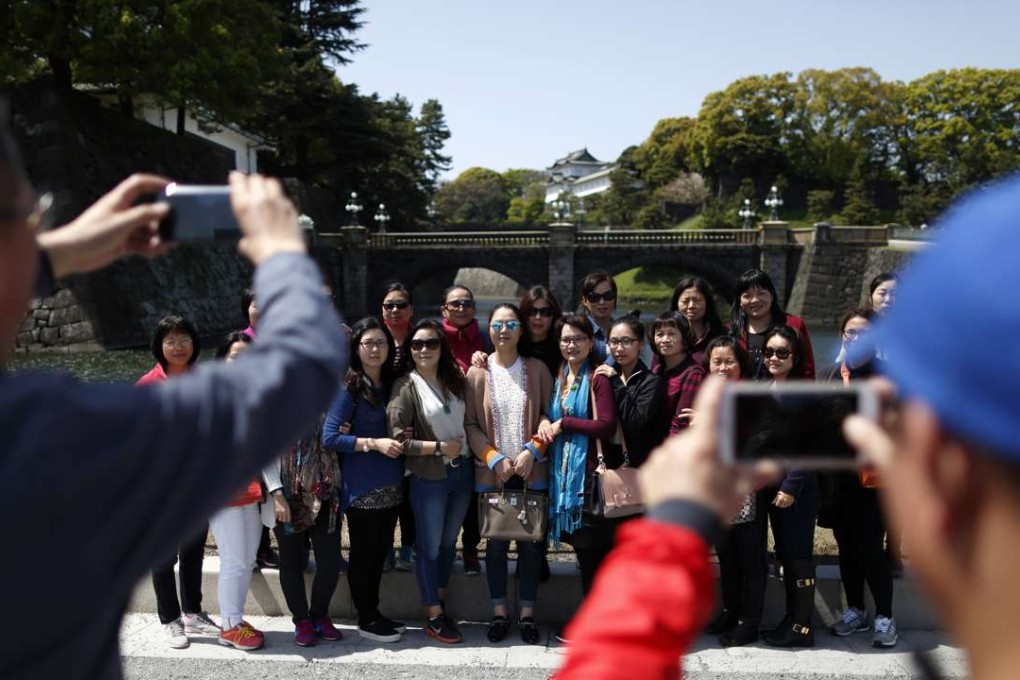 Tourists from China pose for a group photograph outside the Imperial Palace in Tokyo, Japan, on Friday, April 15, 2016. The Japan National Tourism Organization's monthly statistics on the number of foreign visitors to Japan will be published on Wednesday. Photo: Bloomberg