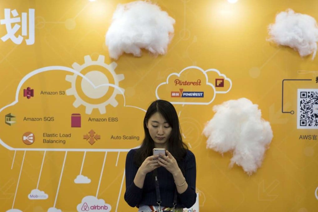 A woman uses her smartphone near a booth promoting cloud services during the Global Mobile Internet Conference in Beijing. Photo: AP