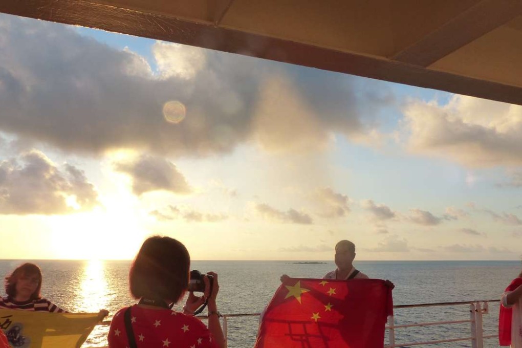 Tourists holding Chinese national flag take photo at sunrise on the Star of Northern Bay. Photo by Liu Zhen