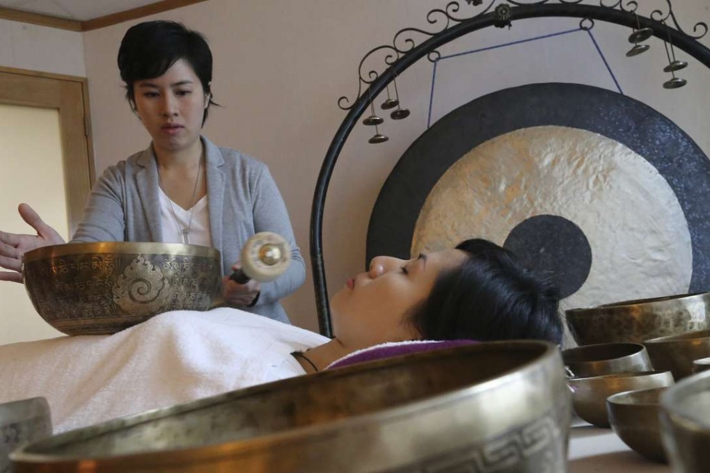 Jasmine Hui (standing) and Jennifer Tang (lying down), founders of Sound Therapy, demonstrate the singing bowls at their Wan Chai centre. Photo: Dickson Lee