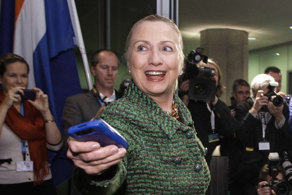 In this 2011 file photo, then-Secretary of State Hillary Clinton hands off her mobile phone after arriving for a meeting in The Hague, Netherlands. By then, concerns had already been raised about her use of a private e-mail server. Photo: AP