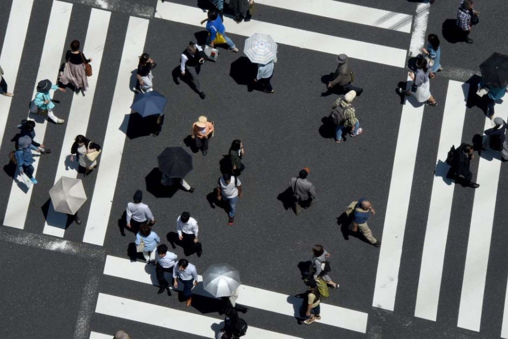 Pedestrians cross a street in Tokyo. Quantitative easing stopped a debt implosion, but its initial success enabled politicians to avoid structural reforms. The result was slower growth from declining productivity, even as companies and governments continued to borrow. In short, we are in a debt trap. Photo: AFP