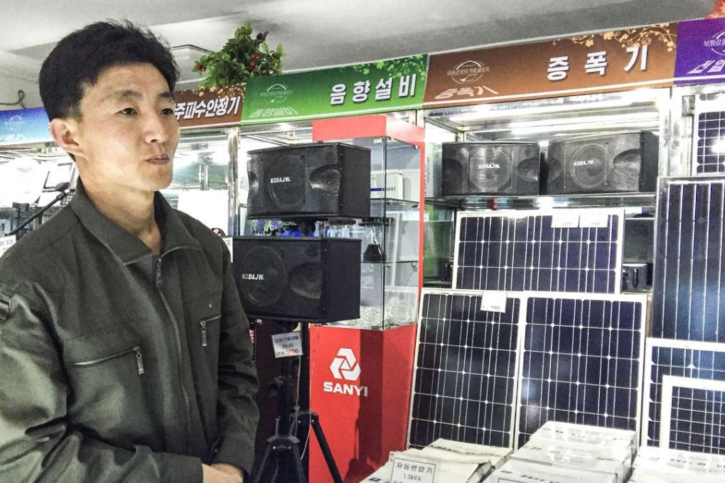 A clerk at the Potanggang Information Technology Center stands in front of a display of solar panels for sale in Pyongyang, North Korea. Photo: TNS
