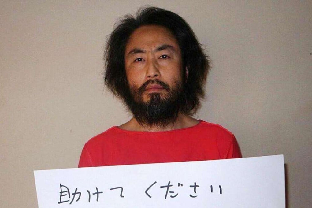 Japanese freelance journalist Junpei Yasuda holding a piece of paper with a handwritten message in Japanese that says: "Please help. This is the last chance. Jumpei Yasuda." Photo: AFP